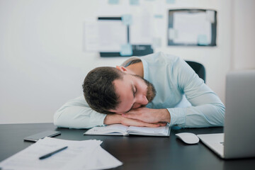 Fototapeta na wymiar young bearded tired man sleeping on office table after hard working day in his modern office, work routine concept