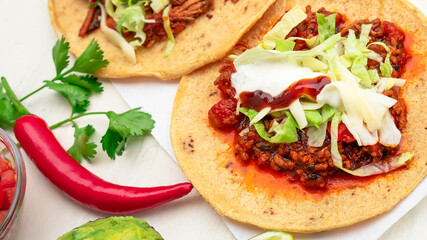 Mexican traditional authentic homemade tacos with pulled pork beef chili con carne serve with tomato salad and avocado guacamole and dip sauce