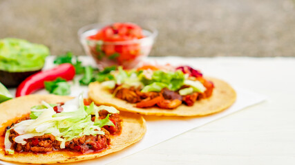 Mexican traditional authentic homemade tacos with pulled pork beef chili con carne serve with tomato salad and avocado guacamole and dip sauce