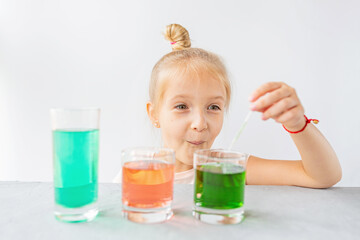 cute little girl six years old doing laboratory experiment with colorful water in classroom. Education science concept. Selective focus. Distance learning during covid-19 coronavirus quarantine.