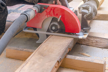 Carpenter cuts wooden board with hand-held circular saw