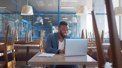 African young entrereneur working on laptop prepraing for opening cafe