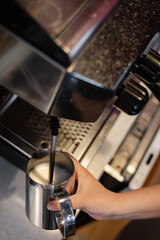 Barista steaming milk for hot cappuccino with machine