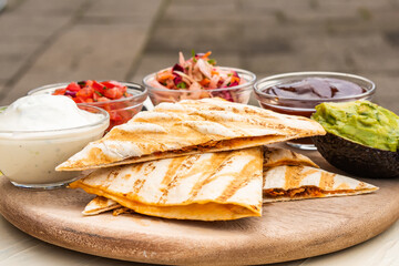 Mexican traditional authentic homemade quesadilla with pulled pork beef chili con carne serve with tomato salad and avocado guacamole and dip sauce