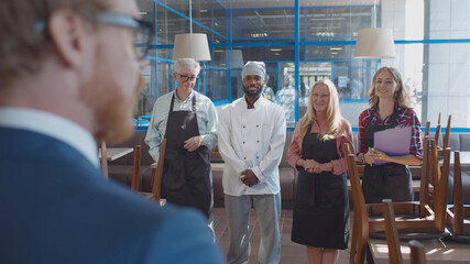 Close up back view of young cafe manager instructing staff before opening