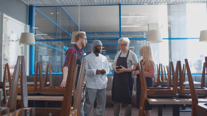 Senior restaurant manager communicating with staff after closing cafe in evening.