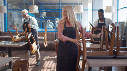 Happy diverse restaurant team preparing place for cleaning after closing in evening
