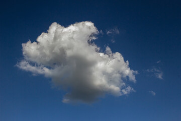 Single cloud in the gradient blue sky. White cloud only one on the blue sky background in daytime.
