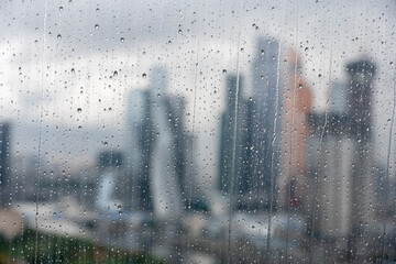 a view of a big city through the window where you can see that it is raining outside