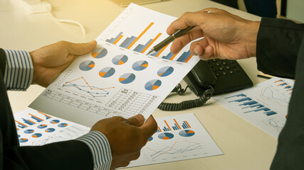 Picture of two young businessmen analyzing graph at the meeting