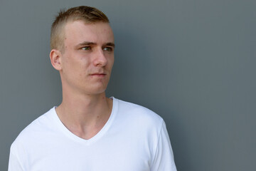 Fototapeta premium Portrait of young blond man against concrete wall outdoors