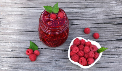Homemade raspberry jam and fresh raspberry in white bowl on the rustic wooden table. Organic Raspberry. Healthy breakfast, vegan vegetarian diet. Fresh farm berries