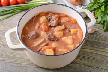 Pot with tasty beef stew on table