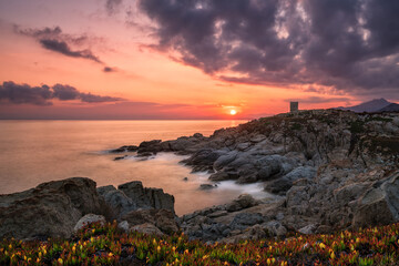 Sun rising behind genoese tower in Corsica