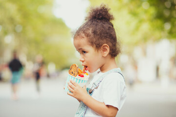 Cute little girl eating ice-cream in the street