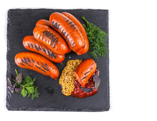 grilled sausages, mustard seeds, ketchup, Basil and parsley on a stone tray, white isolated background