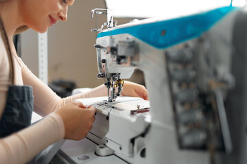 Seamstress woman at her workplace sewing clothes on sewing machine