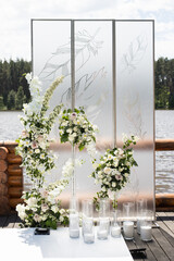 Vertical photo of wedding ceremony with white transparent screens and fresh white flowers and candles