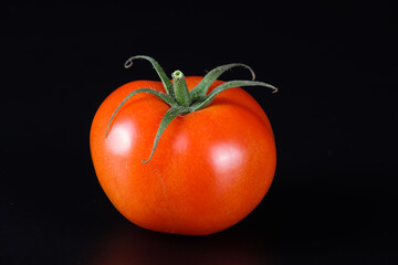 Eine einzelne saftige rote Tomate vor einem neutralen tiefschwarzen Hintergrund