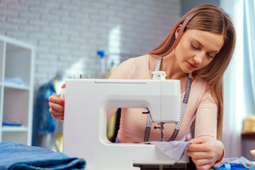 Young seamstress working on her sewing machine on textile factory