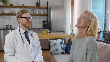 Smiling young doctor giving high five to mature woman