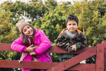 Children standing on a wooden fence.  They enjoy a sunny day outdoors.  It's an autumn day.