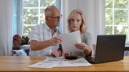 Mature married couple doing family finances at home.