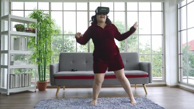 Asian fat woman in Virtual Reality or VR goggle wearable exercise dancing fitness at home, New normal personalize technology simulation concept