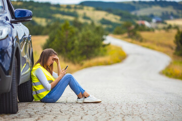 Young woman standing by her broken car on the road and using phone to call for help. Hello, I have a problem with my car! Young Woman calling for assistance with his car broken down by the roadside