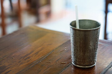 The white drinking straw in a metal glass that has cold water until steam condenses on the side of the glass.