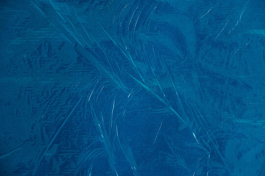 Wrinkled transparent plastic texture on an blue background. Transparent cellophane texture on an yellow backing. Top view. Copy, empty space for text