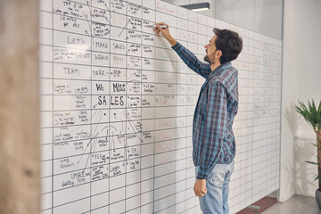 Fototapeta premium Male worker writing on whiteboard in office
