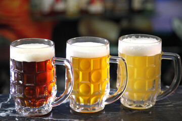 Glasses with different sorts of craft beer. Red, bronze and white beer in beer glasses on the bar. Glasses of light and dark beer on a pub background. 