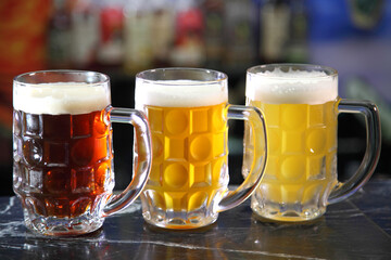 Glasses with different sorts of craft beer. Red, bronze and white beer in beer glasses on the bar. Glasses of light and dark beer on a pub background. 