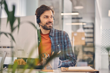 Joyful male worker sitting at the table in office