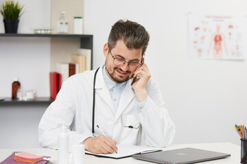 doctor talking on phone and noting down the data