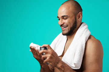 Happy african american man with towel holding shaving foam