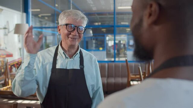 Diverse waiters giving each other high-five in restaurant