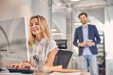 Fototapeta premium Joyful young woman using computer at work