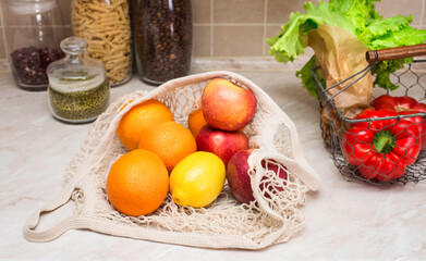 Eco friendly mesh bag with fruit and veggies at the kitchen table. No plastic. Zero waste and plastic free concept. Grocery shopping with eco bag. Sustainable and eco friendly lifestyle concept.