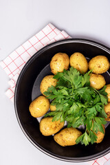 Organic Young Roasted Potatoes on Black Plate Decorated with Parsley Top View Vertical