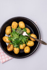 Organic Young Roasted Potatoes on Black Plate Decorated with Parsley Top View Vertical