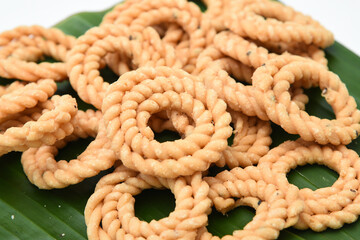 Rice savoury, murukku, chakli, chakali, popular deep fried traditional South Indian tea time snack on banana leaf, Kerala India. made in coconut oil on Onam, Vishu, Diwali, Deepawali, Ramzan, Eid.