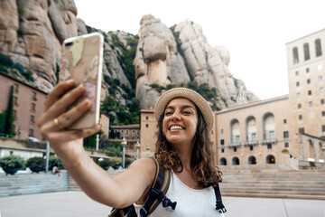 Naklejka na ściany i meble Woman taking a selfie photo in the montserrat monastery, Barcelona, Spain