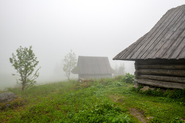 Stare drewniane chaty pasterzy spowite w gęstej mgle. Tatry, Polska © Kamil_k2p