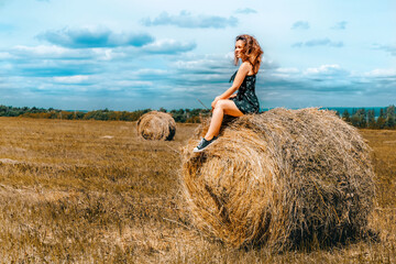 Naklejka na ściany i meble Country concept young woman sitting on haystack in summer 