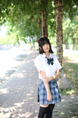 Asian school girl walking and looking in urban city with tree background