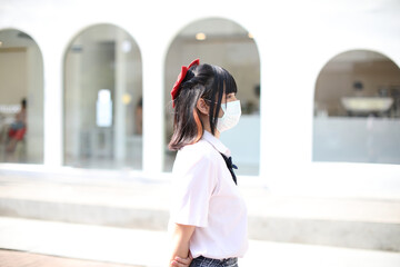 Asian school girl with mask in urban city with tree background