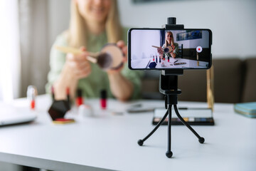 makeup blogger influencer recording tutorial video with phone for social media at home