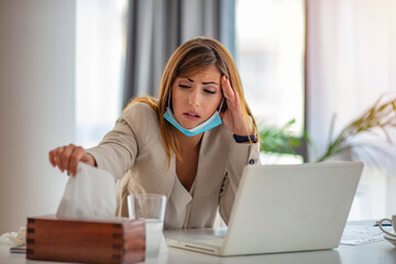 Shot of a young businesswoman blowing her nose in an office. Trying to beat the flu. These...